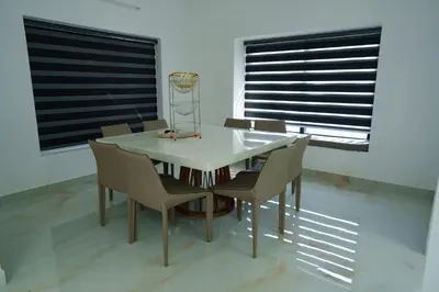 a dining room with a white table and chairs at KiwiOz Villa in Thamarassery