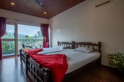 a bedroom with a bed with a red blanket on it at Misty Creek Homestay in Vālpārai
