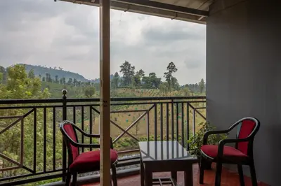 a balcony with two chairs and a table and a view at Misty Creek Homestay in Vālpārai