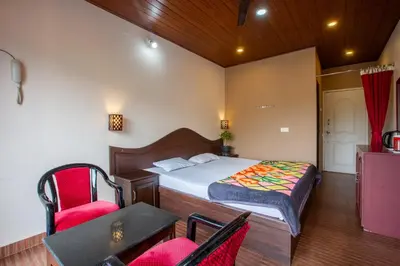 a bedroom with a bed and two red chairs at Misty Creek Homestay in Vālpārai