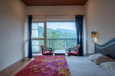 a bedroom with a bed and two chairs and a balcony at Misty Creek Homestay in Vālpārai