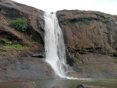 a waterfall on the side of a cliff at Boganvilla, Magic Land Resort in Athirappilly