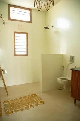 a bathroom with a toilet and a rug on the floor at Villa Vani in Mysore