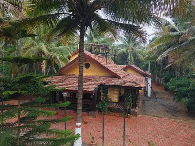 a house with a palm tree in front of it at SS Farms By Shivalaya Stays in Alāndurai
