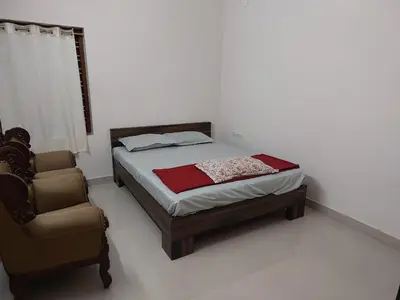 a bedroom with a bed and a chair at Real Estate GURUVAYOOR in Trichūr