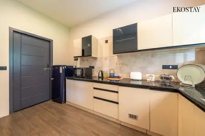 a kitchen with a black counter top and a refrigerator at EKOSTAY - Amber Villa in Kodaikānāl