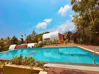 a large swimming pool in front of a building at Talenresort Vythiri Villas in Wayanad