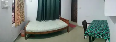 a small room with a bed and a table and a bed petertodd at Aswathy Bhavan in Vadakkāncheri
