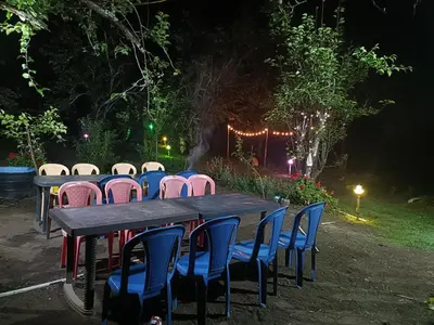 a wooden table with chairs around it at night at Croods cabin in Kodaikānāl