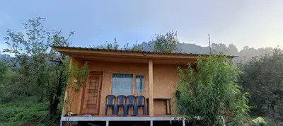 a small house with three blue chairs on the porch at Croods cabin in Kodaikānāl