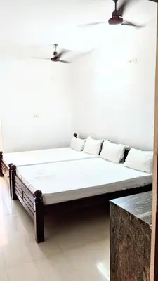 a bed in a room with white sheets and pillows at PALLIYARAI GARDENS LODGE AND HOMESTAy in Palani