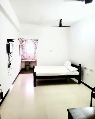 a room with a bed and a tv in it at PALLIYARAI GARDENS LODGE AND HOMESTAy in Palani