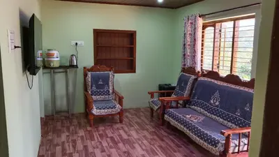 a living room with two chairs and a window at Ammavvana Kutira Home stay in Madikeri