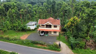 a house with a red roof on the side of a road at Coffee View Holiday Homes in Thirunelli
