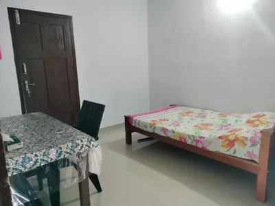 a room with two beds and a table and a door at Aswathy Bhavan in Vadakkāncheri