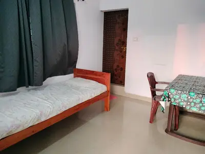 a room with a bed and a table and a chair at Aswathy Bhavan in Palakkad