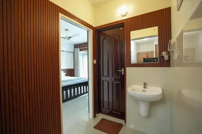 a bathroom with a sink and a toilet and a mirror at Sancta Maria Lounge -cochin Airport in Nedumbassery