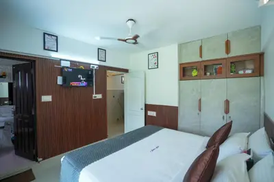 a bedroom with a white bed and a tv at Sancta Maria Lounge -cochin Airport in Nedumbassery