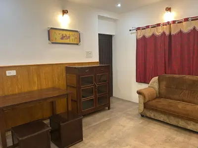 a living room with a couch and a red curtain at Franklin's Finestay in Kotagiri