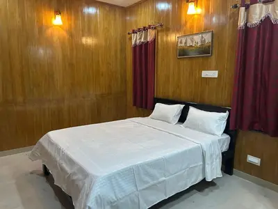 a bedroom with a bed with wood paneling and avertisement at Franklin's Finestay in Kotagiri