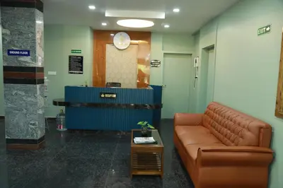 a waiting room with a leather couch and a clock at Marina Tower & Regency Changaramkulam in Edappāl