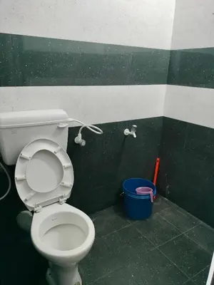 a bathroom with a toilet and a blue bucket at Aswathy Bhavan in Vadakkāncheri