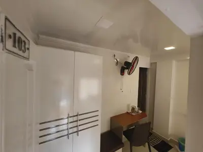 a room with a white cabinet and a table and a desk at Cocoa Tree Munnar in Munnar