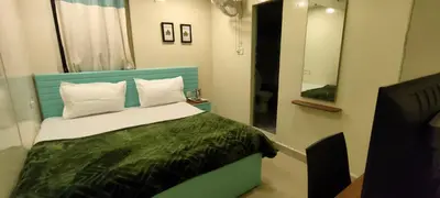 a bedroom with a bed with a green headboard and a mirror at Cocoa Tree Munnar in Munnar