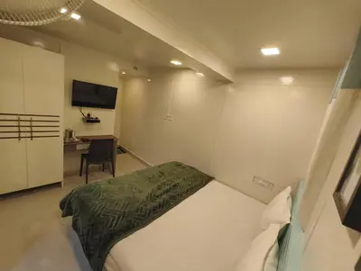a small bedroom with a bed and a desk at Cocoa Tree Munnar in Munnar