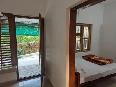 a bedroom with a bed and a large window at Milu Homes in Thirunelli
