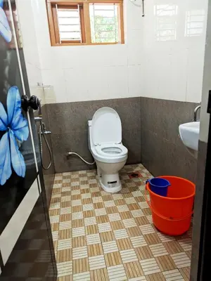 a bathroom with a toilet and a sink and a bucket at Milu Homes in Thirunelli