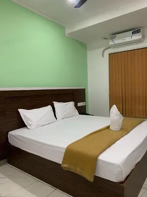 a bedroom with a large bed with white sheets at Adi Deva Inn in Guruvāyūr