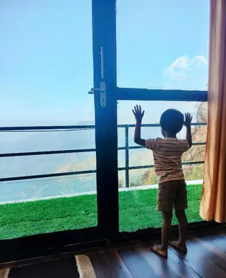 a little boy standing in front of a window at Cocoon Creek in Kodaikānāl