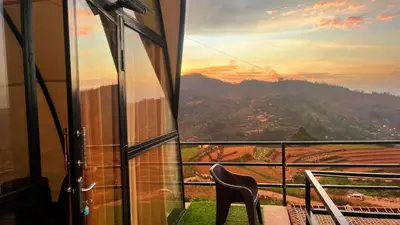 a chair in a room with a view of a mountain at Cocoon Creek in Kodaikānāl