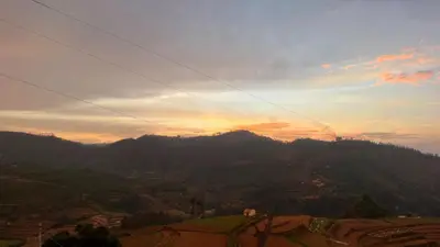 a view of a mountain with the sunset in the background at Cocoon Creek in Kodaikānāl