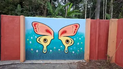 a mural of a butterfly on a fence at Natura Homestay in Padinjarathara