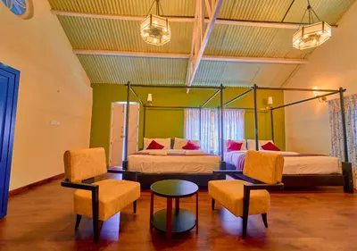 a bedroom with two beds and a table and chairs at Mowbray House Resort Ooty by VOYE HOMES in Ooty