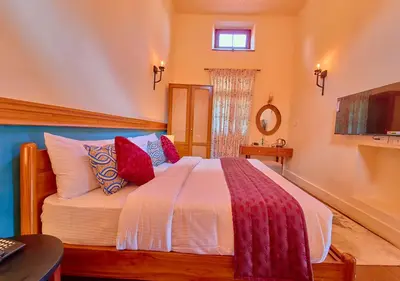 a bedroom with a large bed with red pillows at Mowbray House Resort Ooty by VOYE HOMES in Ooty