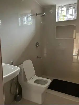 a white bathroom with a toilet and a sink at Airy haven in Kushālnagar