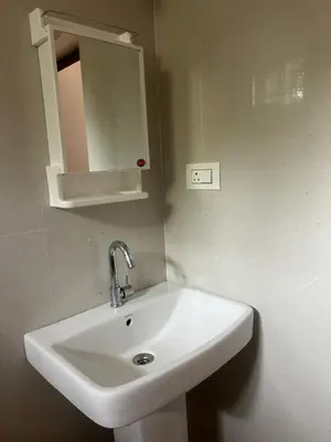 a bathroom with a white sink and a mirror at Airy haven in Kushālnagar
