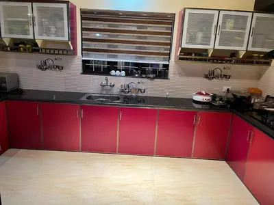 a kitchen with red cabinets and a sink at Sunset View Inn in Irinjālakuda