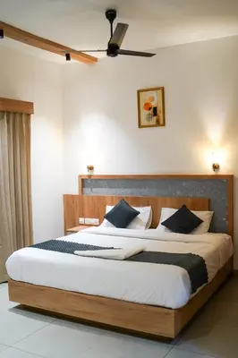a bedroom with a large bed with a wooden headboard at Fog Land Pool Villa by BMT in Vythiri