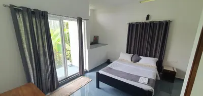 a bedroom with a bed and a large window at Parthees Homestay in Meppādi