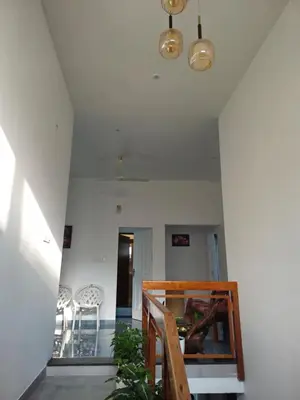 a room with a staircase with a table and chairs at Parthees Homestay in Meppādi