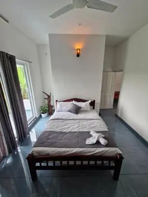 a bedroom with a bed with a white dog laying on it at Parthees Homestay in Meppādi