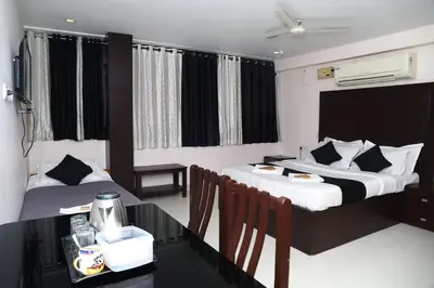 a hotel room with two beds and a table with chairs at Erica Hotel International in Perintalmanna