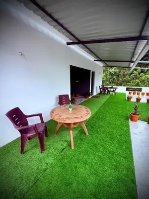 a room with a table and chairs and green grass at Anya Retreats Nature Homestay in Kushālnagar