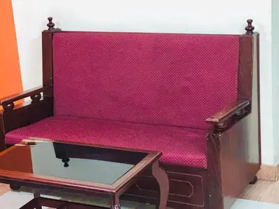 a wooden bench with a pink seat and a table at Hotel Alsaj in Alwaye