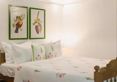 a bedroom with a white bed with three pictures on the wall at SaffronStays Amaya - 5BR 300-year-old Kerala-style heritage villa with spa near Kannur Airport in Irikkūr