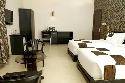 a hotel room with two beds and a table at Rydges Inn in Kottakkal